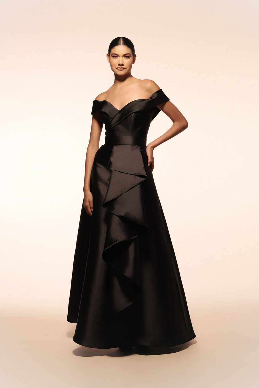 Vestido de gala Benito Santos color negro con escote barco y falda de línea A con detalle de olanes verticales.