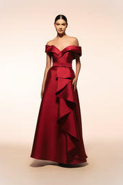 Vestido de gala Benito Santos color tinto con escote barco y falda de línea A con detalle de olanes verticales.