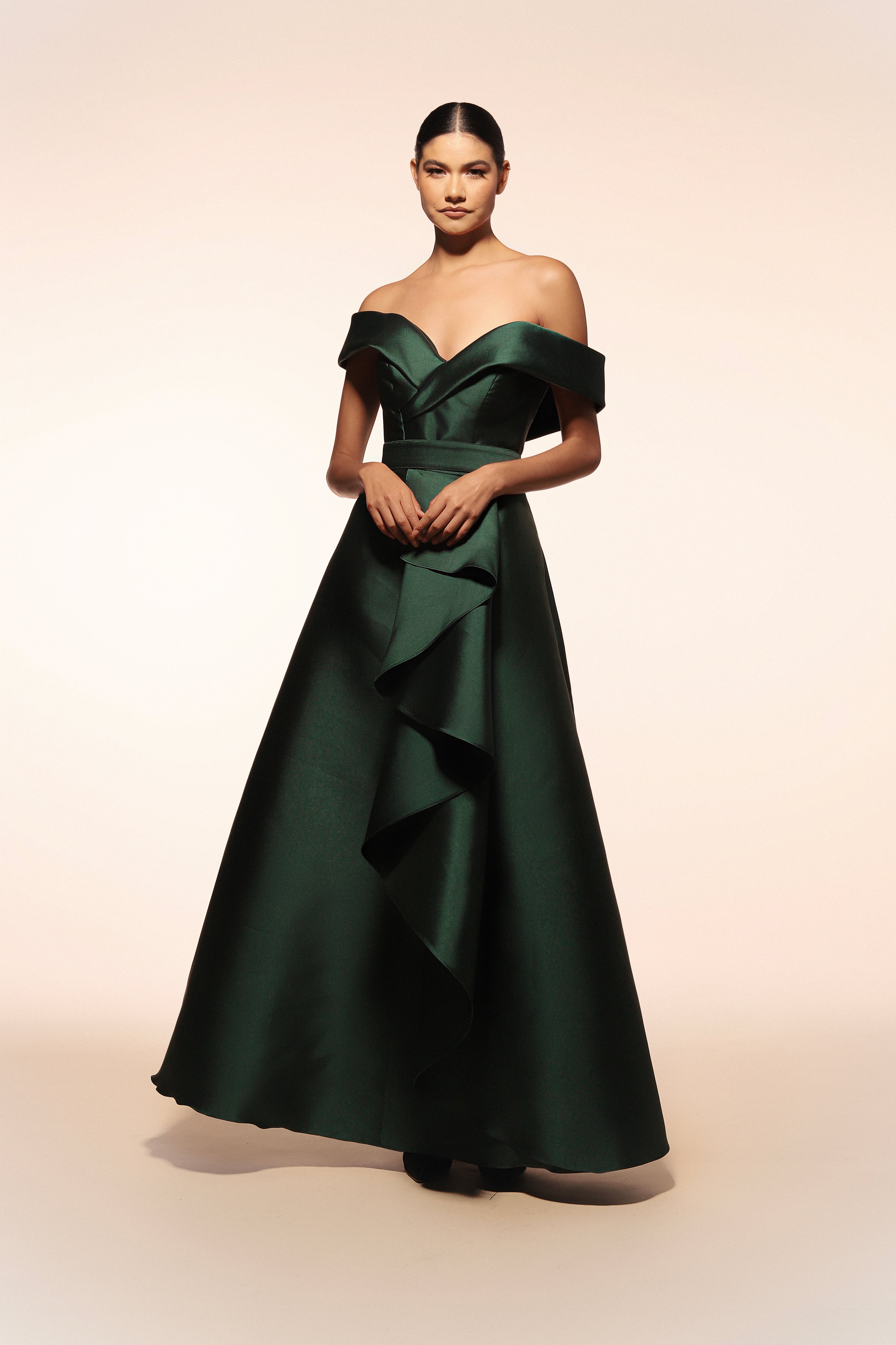 Vestido de gala Benito Santos color verde con escote barco y falda de línea A con detalle de olanes verticales.