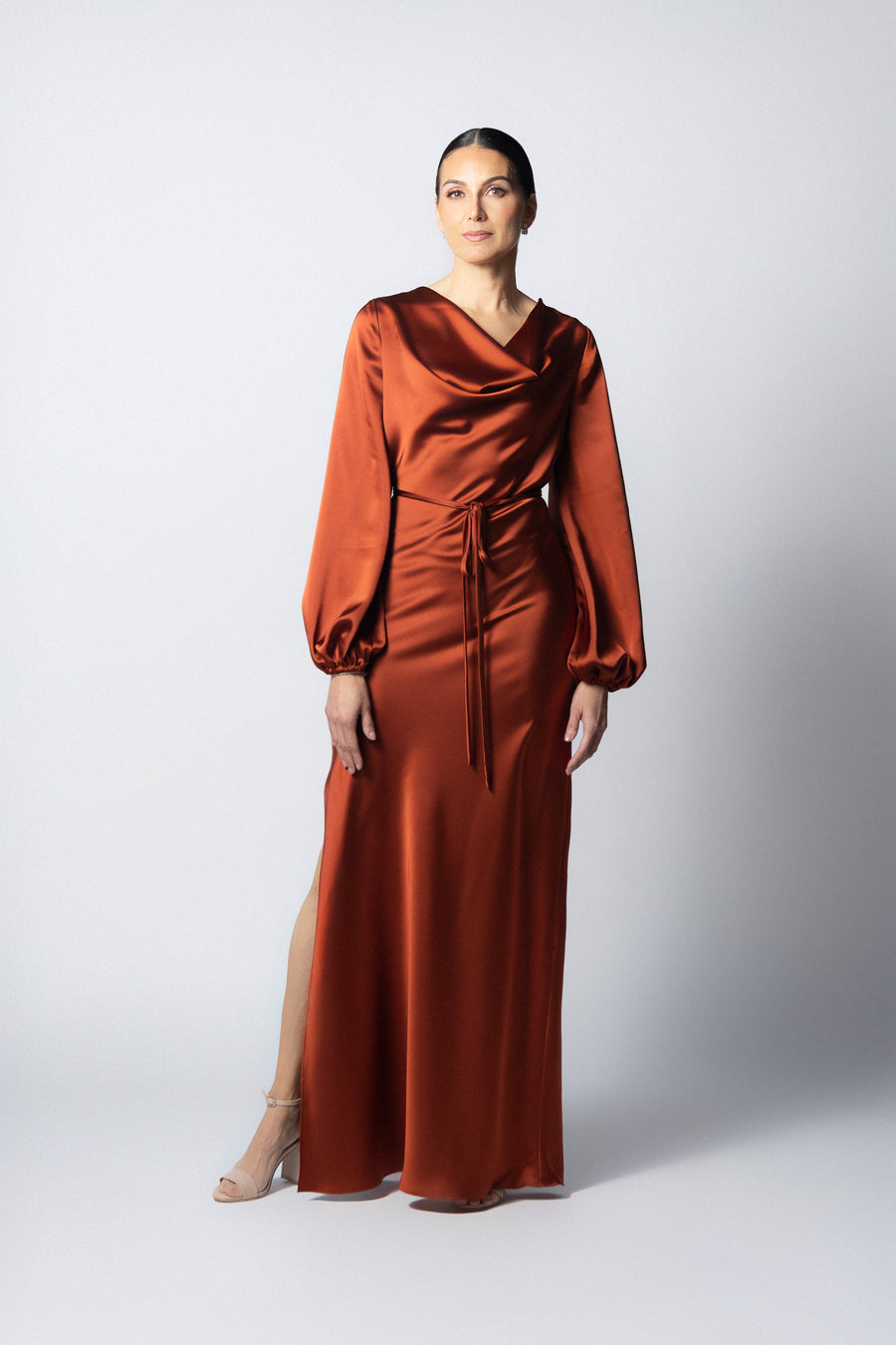 Vestido maxi de satín color óxido con cuello drapeado, mangas largas abullonadas y apertura lateral en la pierna.